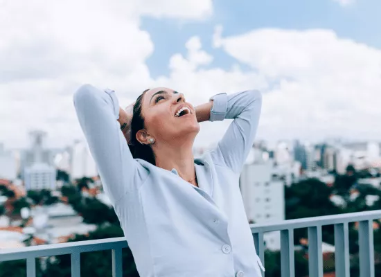 Femme heureuse, les bras croisés derrière la tête, prenant une grande inspiration pour emplir ses poumons